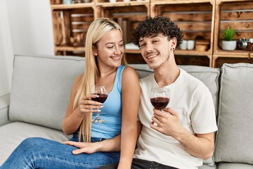 Young couple smiling happy toasting with red wine glass at home.