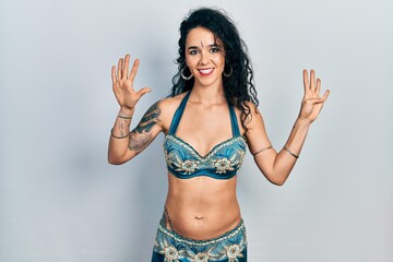 Fototapeta premium Young woman wearing bindi and traditional belly dance clothes showing and pointing up with fingers number nine while smiling confident and happy.
