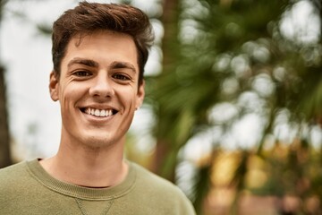Young hispanic man smiling happy standing at the city.