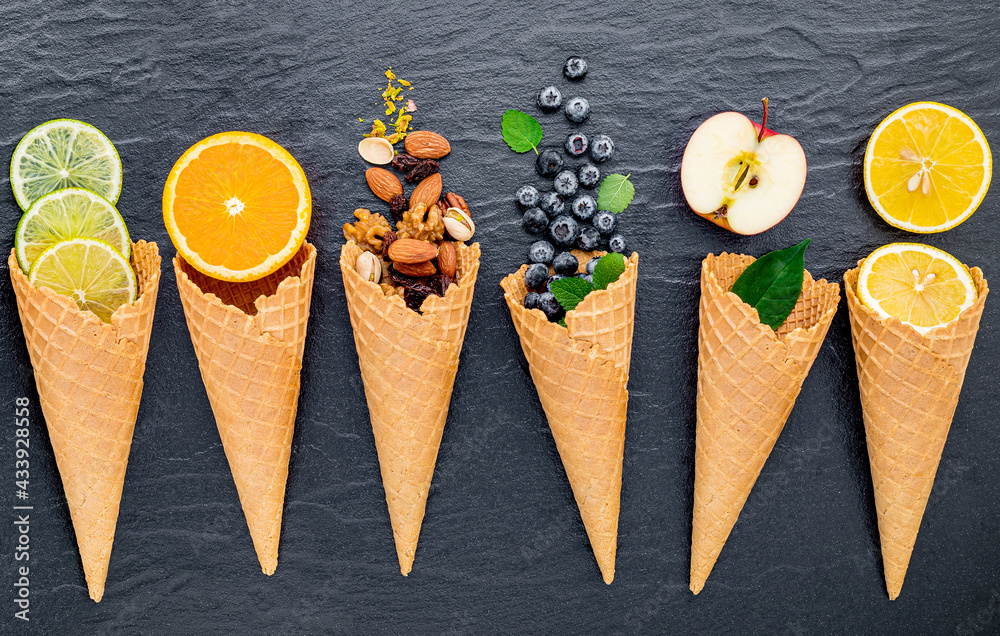 Poster various of ingredient for ice cream flavor in cones set up on dark stone background .