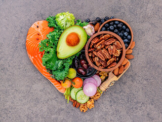 Heart shape of ketogenic low carbs diet concept. Ingredients for healthy foods selection on dark stone background.