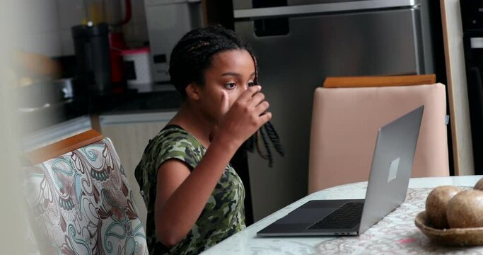 Candid child using laptop, girl adjusting hair while browsing internet
