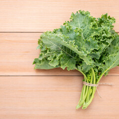 Fresh organic curly kale leaves flat lay on a wooden table with copy space.