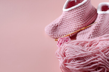 skein of pink yarn crochet and knitted shoes on a colored background knitting concept	