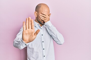 Young hispanic man wearing casual clothes covering eyes with hands and doing stop gesture with sad and fear expression. embarrassed and negative concept.