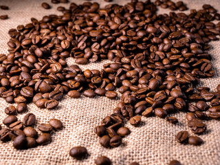 Roasted coffee beans background. Arabica beans on a jute bag. Macro texture of jute cloth with coffe beans on it.