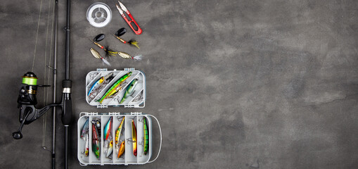 Fishing tackle - fishing spinning rod, hooks and lures on gray background. Active hobby recreation...