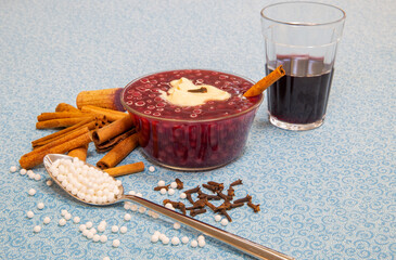 Traditional sweet sagu of red wine with traditional spices, cloves, cinnamon and cream. On a blue fabric towel. Selective focus