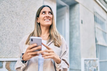 Fototapeta na wymiar Young caucasian woman smiling happy using smartphone at the city.