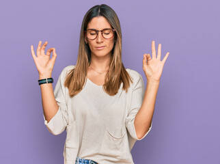 Young woman wearing casual clothes and glasses relax and smiling with eyes closed doing meditation gesture with fingers. yoga concept.