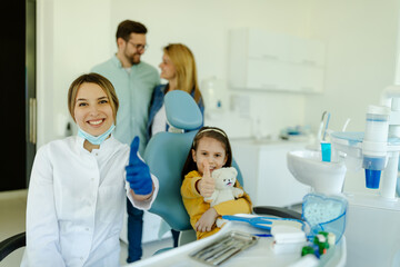 Fototapeta premium A smiling and happy girl posing with her doctor after a successful dental examination.
