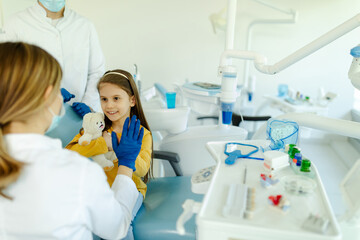 Female doctor is giving hi five to little girl after a successful dental examination.