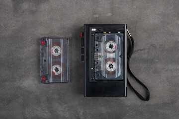 Music listening concept. Vintage cassette tape and audio player close-up on grey concrete background, top view. © Sensay