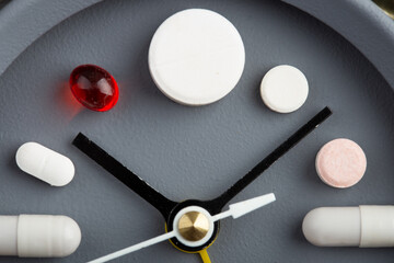 Creative healthcare and medicine concept - clock with drugs and pills.Right time for using medicines. Cold and flu season. Period of diseases