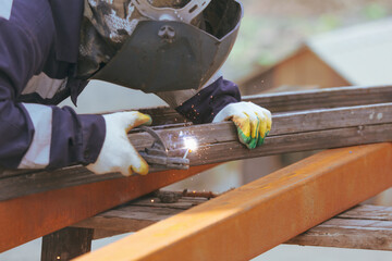 A worker welds metal at a construction site.