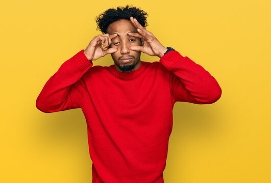 Young african american man with beard wearing casual winter sweater trying to open eyes with fingers, sleepy and tired for morning fatigue