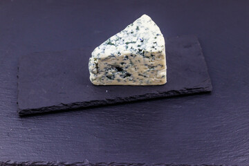 Blue cheese with mold on black slate background