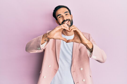 Young hispanic man wearing business jacket smiling in love doing heart symbol shape with hands. romantic concept.