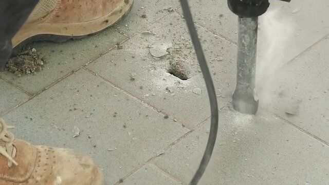 Construction workers breaking and demolishing a cement floor of a house floor for repair. the jack-hammer in SLOW MOTION