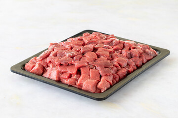 Meat cubes of beef on a white wooden background
