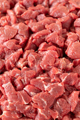 Chopped raw veal meat cubes for saute on white wooden table. Raw Meat backround. Close up meat