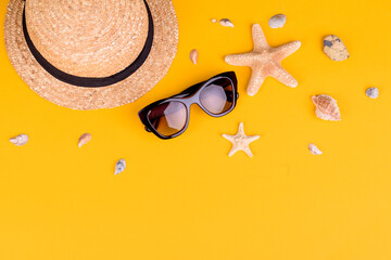 Beach accessories: glasses and hat with shells and sea stars on a colored background