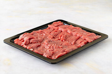 raw vertically sliced beef on a white wooden background.