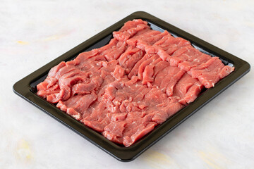 raw vertically sliced beef on a white wooden background.