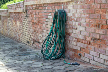 old garden hose hanging on brick wall