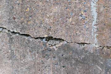 Crack on an old concrete wall. Horizontal fracture. Multi-colored stones.