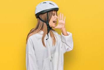 Teenager caucasian girl wearing bike helmet shouting and screaming loud to side with hand on mouth. communication concept.