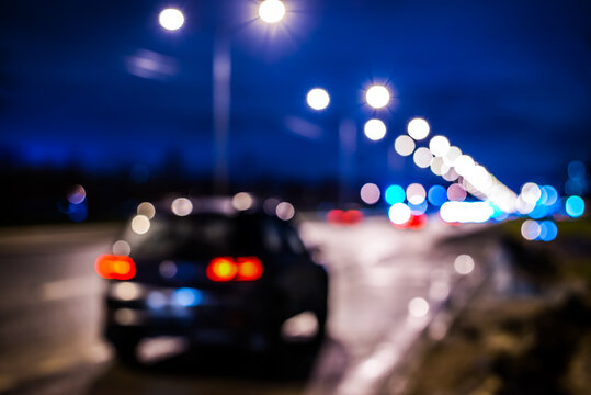 Rainy night in the big city, the big black car parked on the roadside. Defocused image