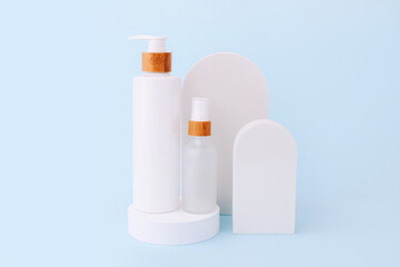 Cosmetic skin care products staying on the geometrical podiums. Product presentation on blue background.