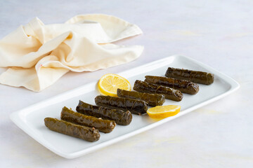 stuffed grape leaves on a white wooden background. Local name zeytinyağlı yaprak sarma