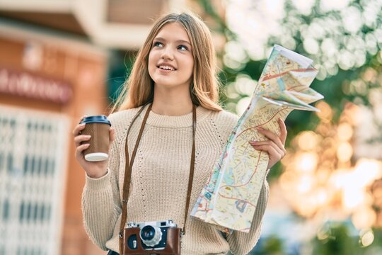 Beautiful caucasian tourist teenager drinking coffee holding map at the city.