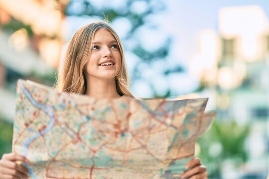 Beautiful caucasian tourist teenager smiling happy holding map at the city.