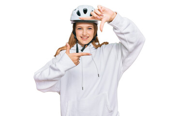 Beautiful young caucasian girl wearing bike helmet smiling making frame with hands and fingers with happy face. creativity and photography concept.