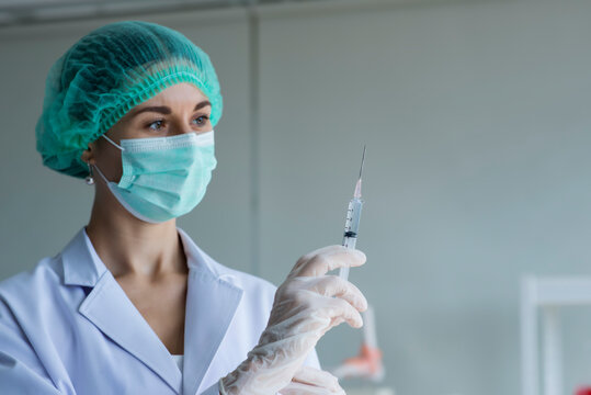 nurse with syringe. medicine, vaccination and healthcare concept -  female doctor or scientist in mask with syringe in hand hold