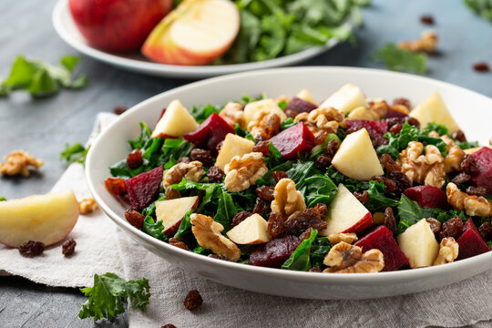 Kale salad with apple, beetroot, walnut and raisins in white plate. Healthy food