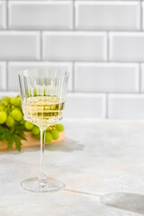 Glass of white wine, bunch grapes. Sun lught and shadow tropic background. Organic antioxidant beverage.