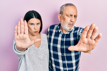 Fototapeta premium Hispanic father and daughter wearing casual clothes doing stop sing with palm of the hand. warning expression with negative and serious gesture on the face.