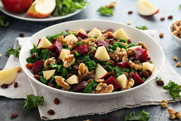 Kale salad with apple, beetroot, walnut and raisins in white plate. Healthy food
