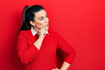 Young hispanic woman wearing casual clothes serious face thinking about question with hand on chin, thoughtful about confusing idea