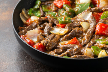 Stir fry Chinese pepper beef steak with onion, red and green bell pepper in pan