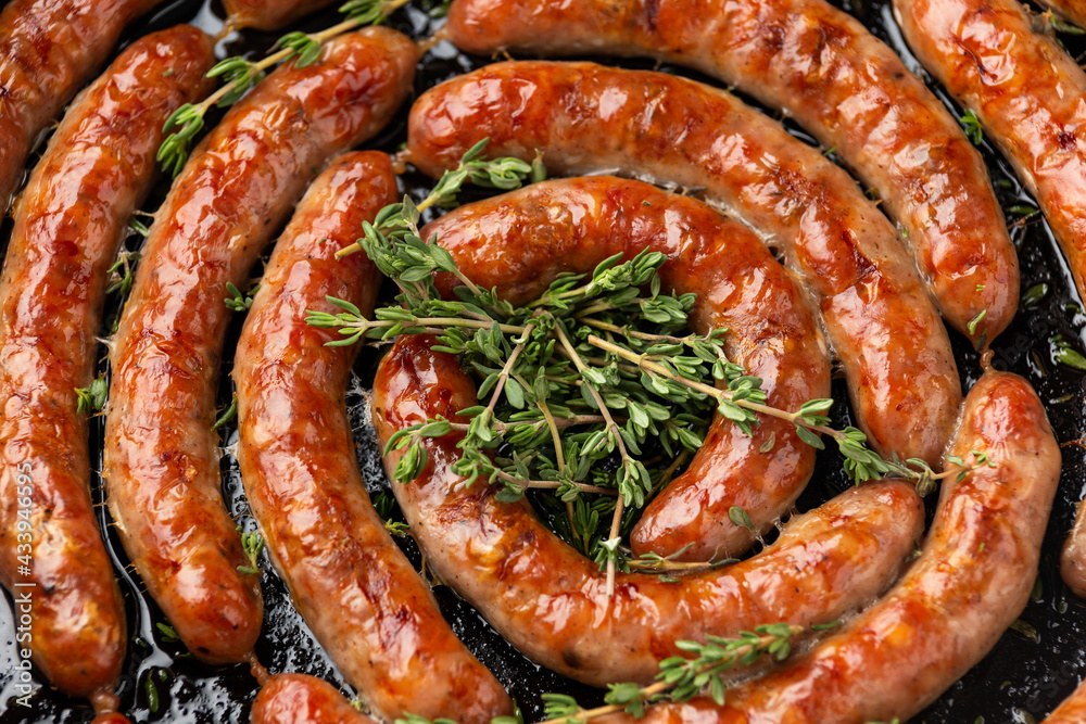 Wall mural homemade pork sausages in rustic pan with thyme