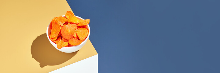 Crispy dried food. Organic tasty chips. Homemade snacks. Sliced carrot. Healthy vegetables. Orange pile Trend natural dish. Horizontal banner. Copyspace