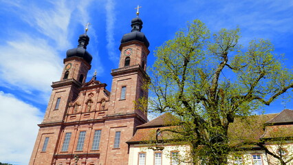 malerische Barockkirche in St. Peter im Schwarzwald  neben grünem Baum unter blauem Himmel