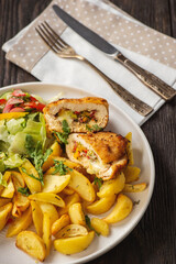 Homemade stuffed chicken breast with roasted potatoes and salad.