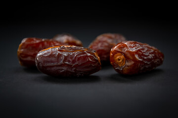 Sweet soft moist natural dates ioslated with a dark background.