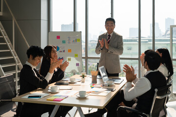 middle age asian executive manager clapping hands with multiracial business team for success of new project in office meeting room
